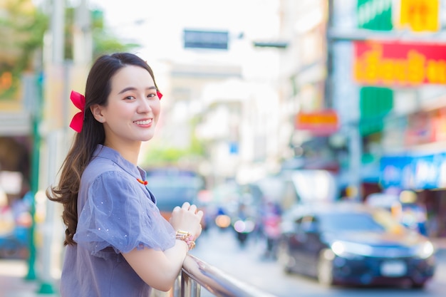 Belle dame asiatique en robe Qipao bleu-gris est debout souriant joyeusement en bordure de China Town