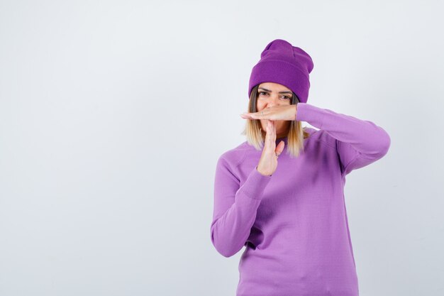 Belle dame en pull montrant un geste de temporisation et ayant l'air fatigué, vue de face.