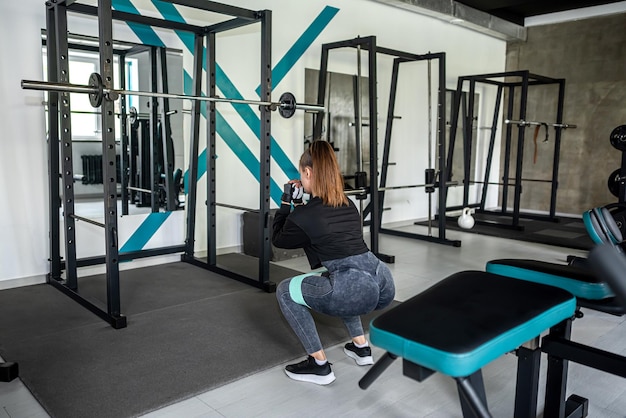 Belle dame de remise en forme travaillant dans la salle de gym faisant des exercices qui pompent les muscles du dos