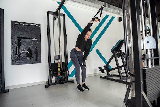 Belle dame de remise en forme travaillant dans la salle de gym faisant des exercices qui pompent les muscles du dos