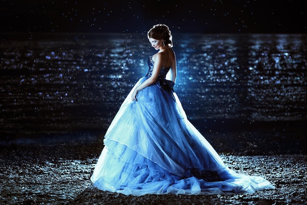 Belle dame en robe bleue marchant près de la mer