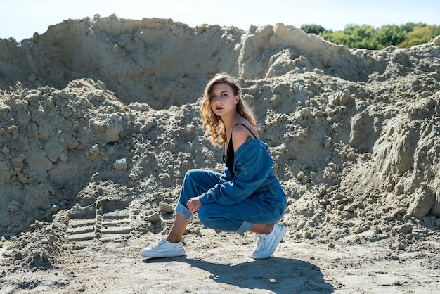 Belle dame en salopette bleue se promène dans une carrière de sable