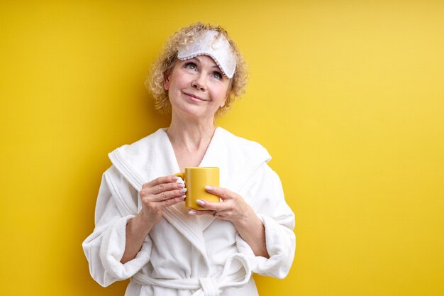 Belle dame senior chaque matin commence avec une tasse de délicieux café, profitant du temps seul, tenant une tasse jaune dans les mains, avant la journée de travail ou le week-end