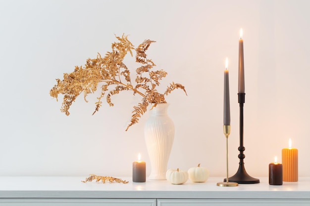 Belle décoration d'automne avec des bougies allumées dans un intérieur blanc