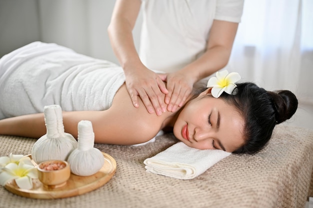 Belle et détendue femme asiatique recevant un massage allongé sur une table de massage dans un salon de spa thaïlandais