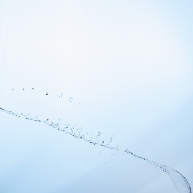 Belle éclabousse une eau propre sur fond dégradé bleu.