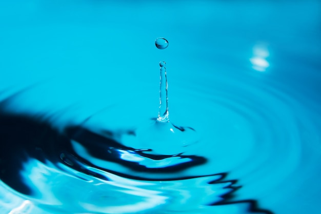 Belle éclaboussure de goutte d'eau sur la surface de l'eau en bleu