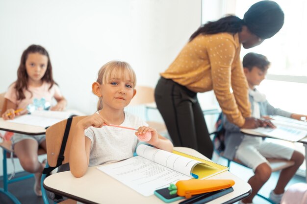 Belle écolière aux yeux bleus assis au bureau en classe