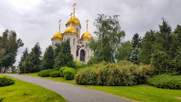 Belle église chrétienne aux coupoles dorées parmi les arbres verts