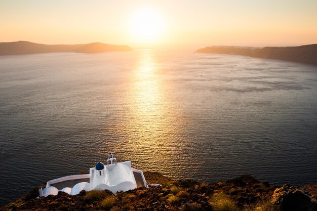 Belle église sur la côte de la mer au coucher du soleil. Île de Santorin, Grèce.