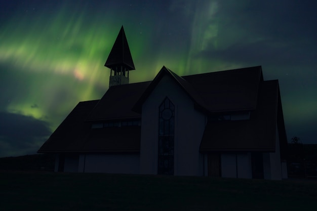 Une belle église traditionnelle près de la ville de Reykjavik une nuit avec de belles aurores boréales. Islande