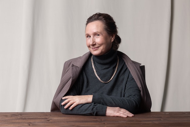 Belle et élégante femme d'affaires âgée caucasienne assise à la table et souriant.