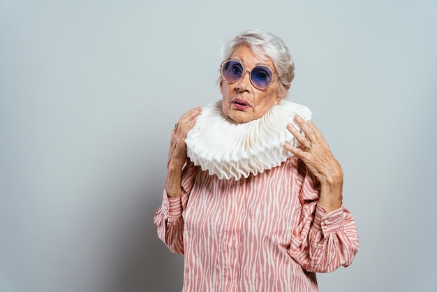 Belle et élégante vieille femme d'influence. Grand-mère cool qui pose en studio avec des vêtements à la mode. Heureuse dame âgée célébrant et faisant la fête. Concept sur l'ancienneté et le mode de vie