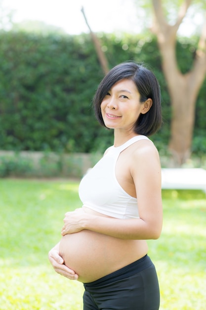 Belle enceinte de portrait asiatique jeune femme se détend dans le parc.