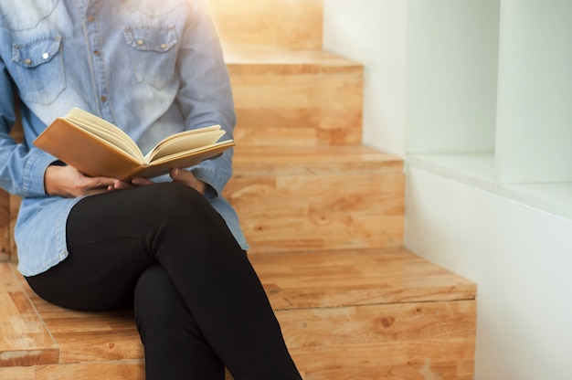 Belle étudiante assis à l&#39;escalier et lire un livre