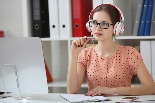 Belle étudiante avec un casque d'écoute de la musique et d'apprentissage. Tenez la poignée dans sa main et regardez le moniteur