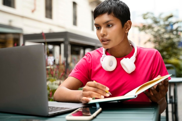 Belle étudiante indienne pensive utilisant un ordinateur portable pour étudier, prendre des notes, éducation en ligne