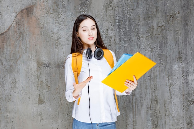 Belle étudiante avec sac à dos et casque portant des livres. Photo de haute qualité