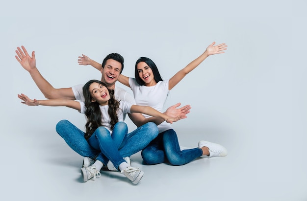 Belle excitée et l'équipe familiale drôle pose dans un t-shirt blanc alors qu'elles sont isolées sur fond blanc en studio.