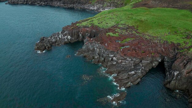 Belle falaise de pierre et eau verte de l'océan avec de petites ondulations clip vue aérienne de la côte rocheuse