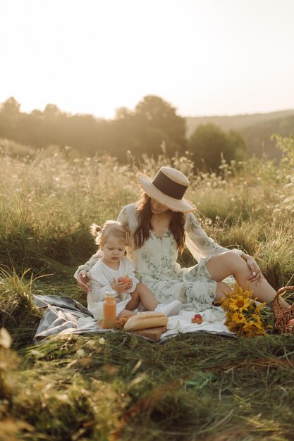 Belle famille caucasienne de père mère et petite fille posant devant la caméra sur fond de champ vert