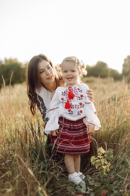 Belle famille avec enfant en costume ethnique traditionnel dans un parc de campagne