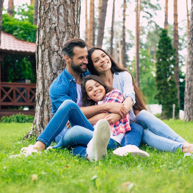 Belle famille heureuse assis ensemble sur l'herbe