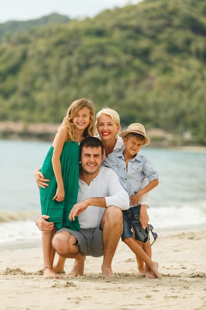 belle famille heureuse en vacances embrassant sur la plage et regardant la caméra