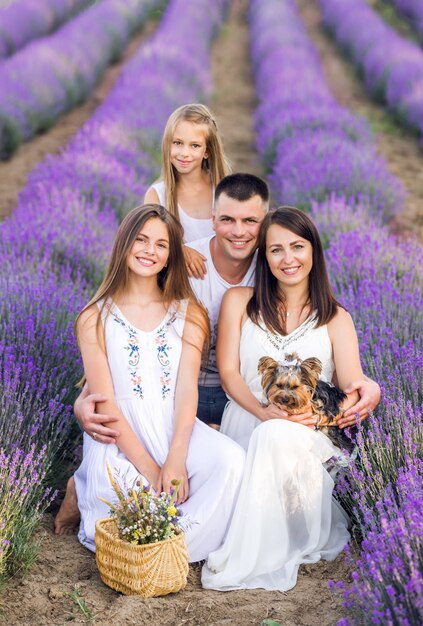 Belle famille et leur petit chien dans un champ de lavande. Photo d'été aux couleurs violettes.