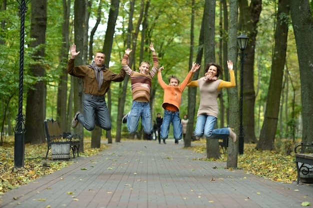 Belle famille de quatre personnes sautant dans le parc d'automne