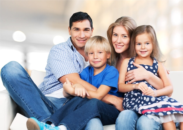 Belle famille souriante assise sur un canapé à la maison