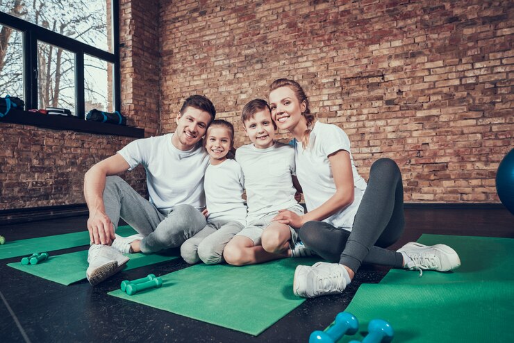 Photo belle famille en t-shirts blancs assis dans le grand gymnase.