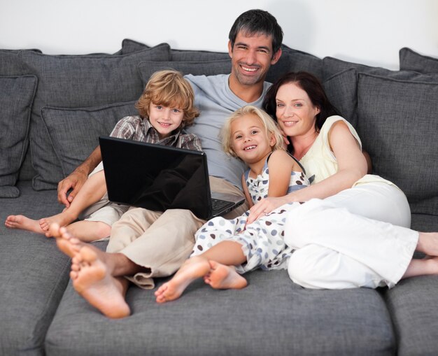 Belle famille en utilisant un ordinateur portable sur un canapé