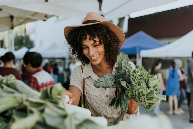 Belle femme achetant le chou frisé à un marché de fermiers