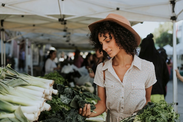 Belle femme achète du chou frisé dans un marché de producteurs