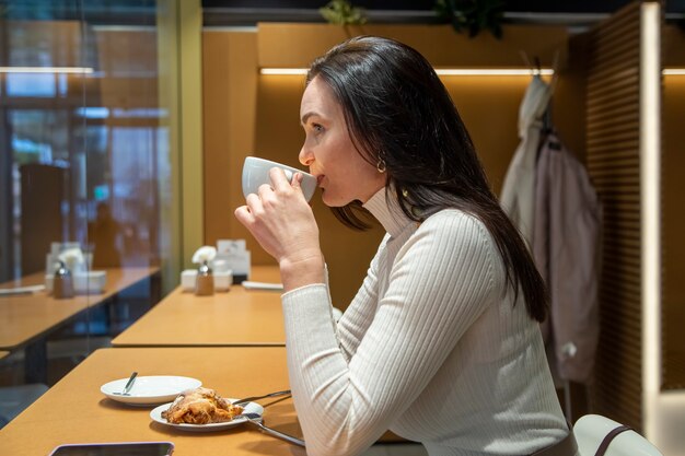 Belle femme adulte buvant du café dans un café