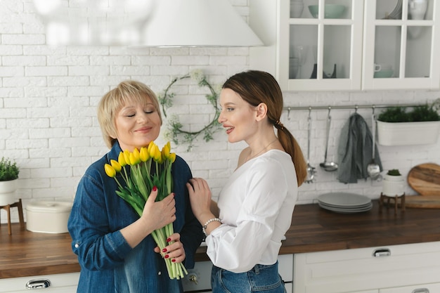 Belle femme adulte donne des fleurs à sa mère mature Womens day