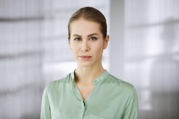 Belle femme d'affaires adulte vêtue d'un chemisier vert debout tout droit au bureau. Portrait ou portrait d'entreprise.