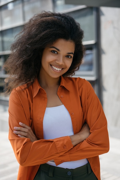 Photo belle femme d'affaires afro-américaine, les bras croisés, debout à l'extérieur, souriant