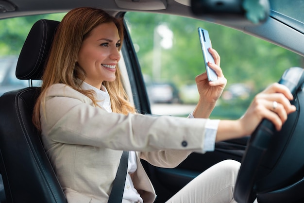 Belle femme d'affaires à l'aide de téléphone portable en voiture. Femme d'affaires conduisant une voiture et utilisant un téléphone