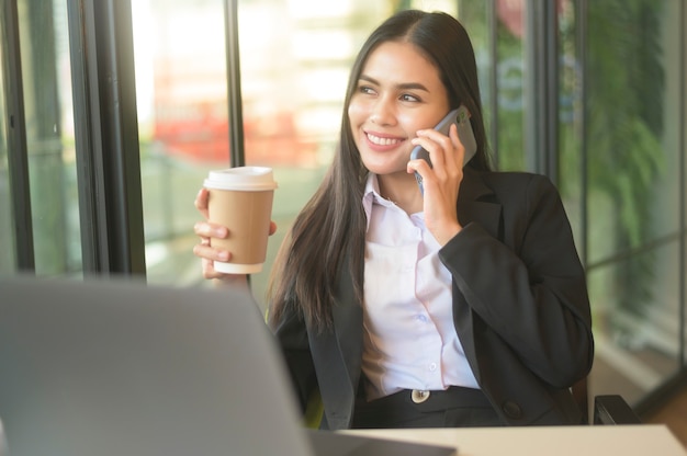 Une belle femme d'affaires analyse les données financières via ordinateur, buvant du café dans un café. mode de vie des gens d'affaires. concept technologique.