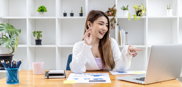 Belle femme d'affaires asiatique assise dans son bureau privé, elle parle à son partenaire par appel vidéo sur son ordinateur portable, c'est une femme cadre d'une start-up. Concept de gestion financière