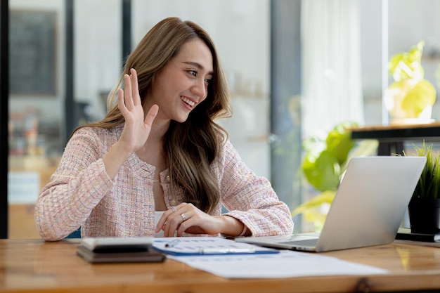 Belle Femme D'affaires Asiatique Assise Dans Son Bureau Privé, Elle Parle à Son Partenaire Via Un Appel Vidéo Sur Son Ordinateur Portable, Elle Est Une Femme Cadre D'une Start-up Concept De Gestion Financière