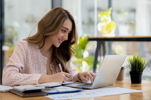 Une belle femme d'affaires asiatique assise dans son bureau privé, elle vérifie les documents financiers de l'entreprise, elle est une femme cadre d'une entreprise en démarrage Concept de gestion financière