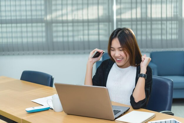 Belle femme d'affaires asiatique travaillant au bureau le soirTravailleur thaïlandais heureux après avoir regardé un ordinateur portableSuccès du travail