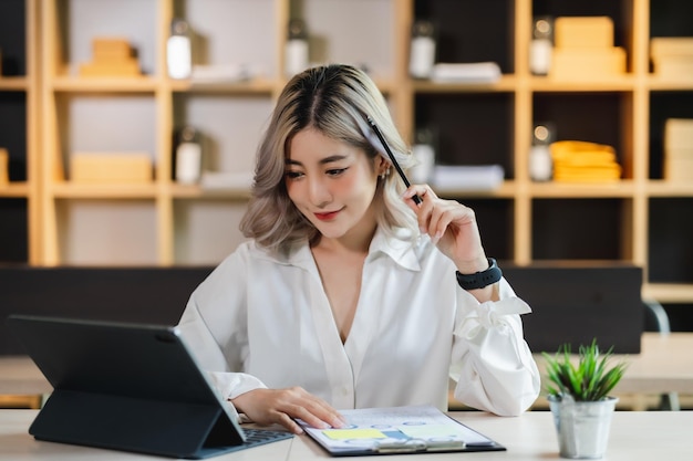 Belle femme d'affaires asiatique travaillant sérieusement en pensant à l'idée de travailler sur ordinateur et penser projet d'idée assis à l'intérieur