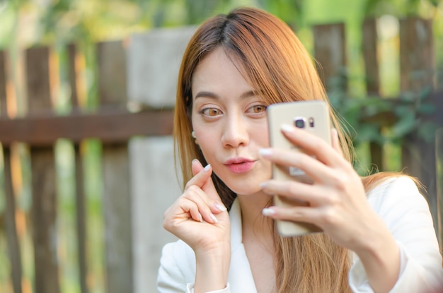 Belle femme d'affaires asiatique utilise un téléphone intelligent selfiegirl prendre une photo pour les médias sociaux actuels
