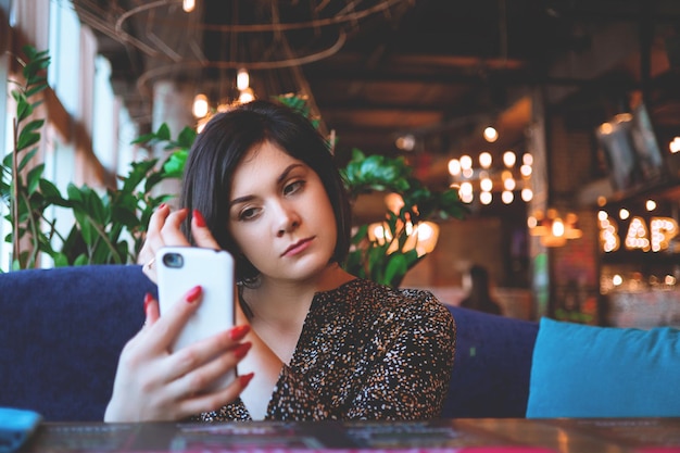 Belle femme d'affaires au restaurant appelle sur votre smartphone Jolie brune dans un café