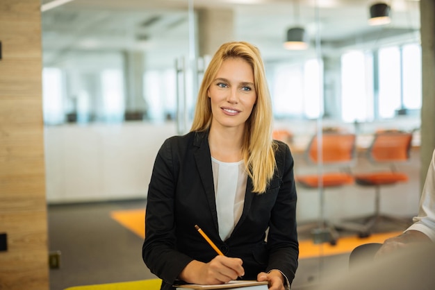 Belle femme d'affaires blonde prenant des notes sur la réunion