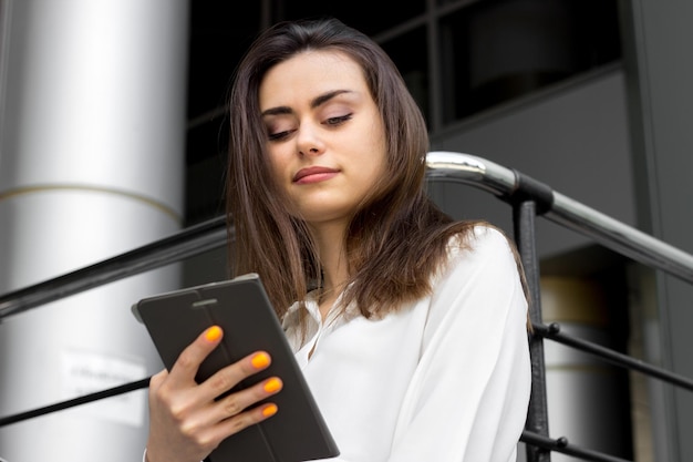 Belle femme d'affaires brune à l'aide d'une tablette mobile à l'extérieur